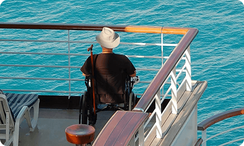 image of man sitting in wheelchair on cruise ship looking out onto the water